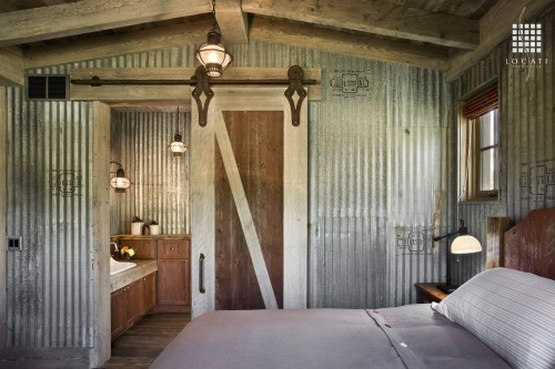 Locati Architects uses industrial metal on the walls of this bedroom to play up the rustic vibe.