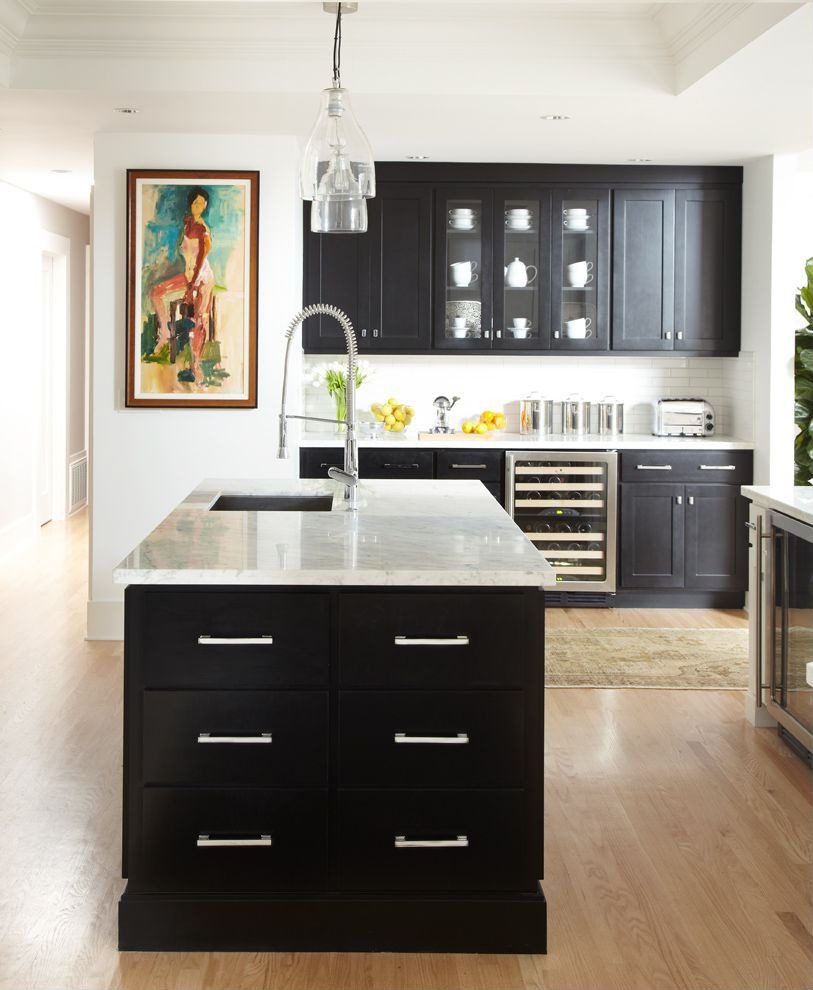 This kitchen by Urrutia Design showcases black cabinets with white marble counters. 